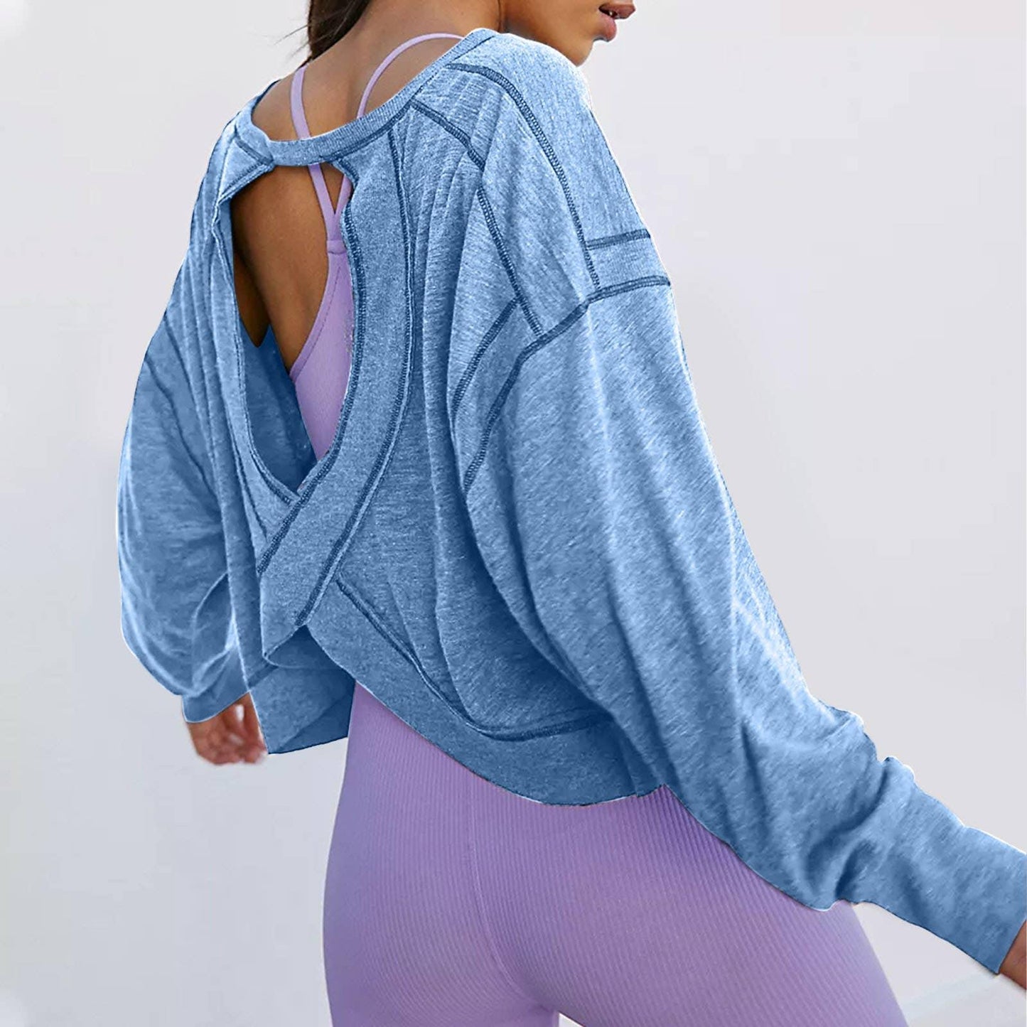 Blue open-back cropped hoodie with long sleeves, paired with purple workout leggings and sports bra