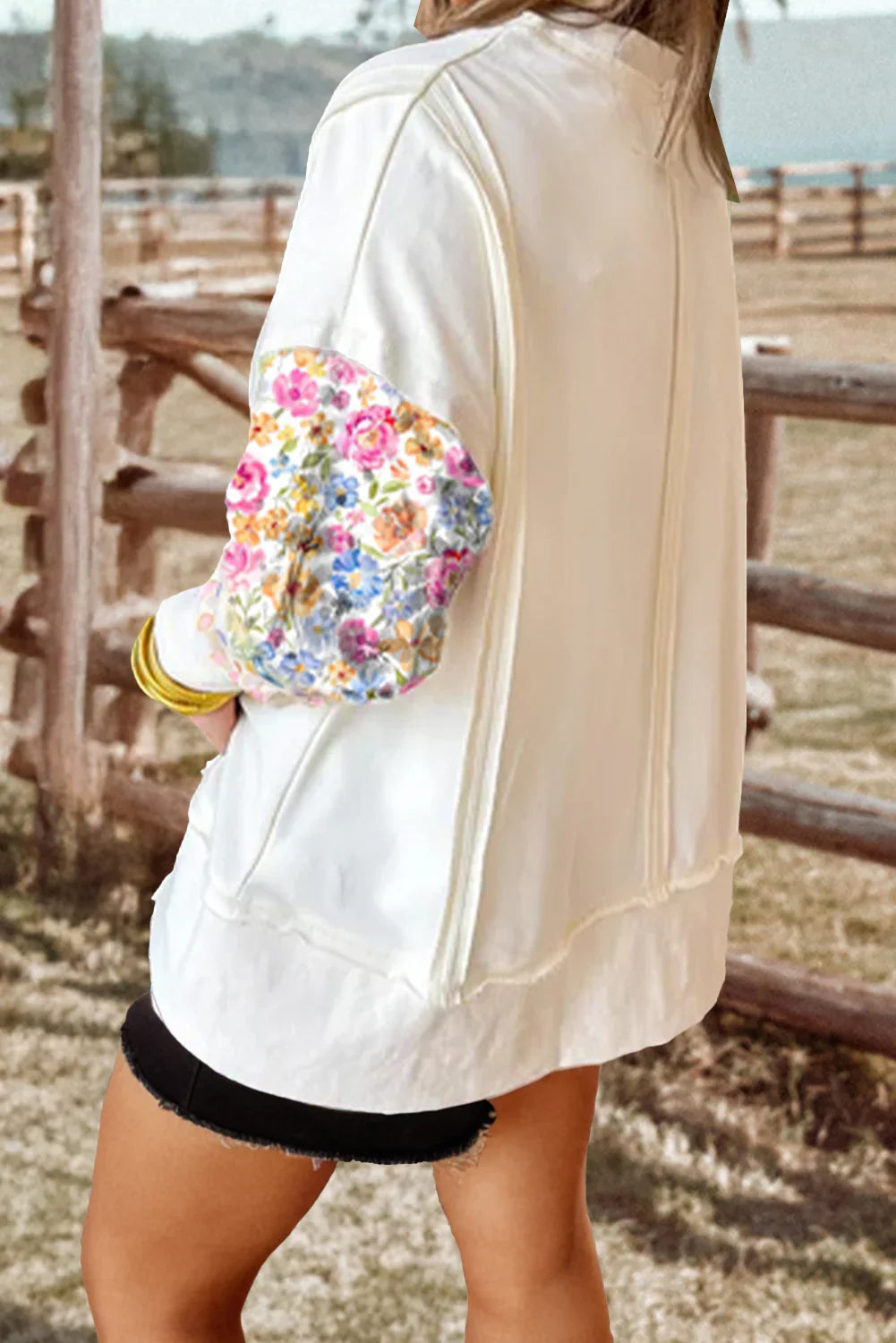 White bomber jacket with floral elbow patch, styled with denim shorts for casual spring fashion