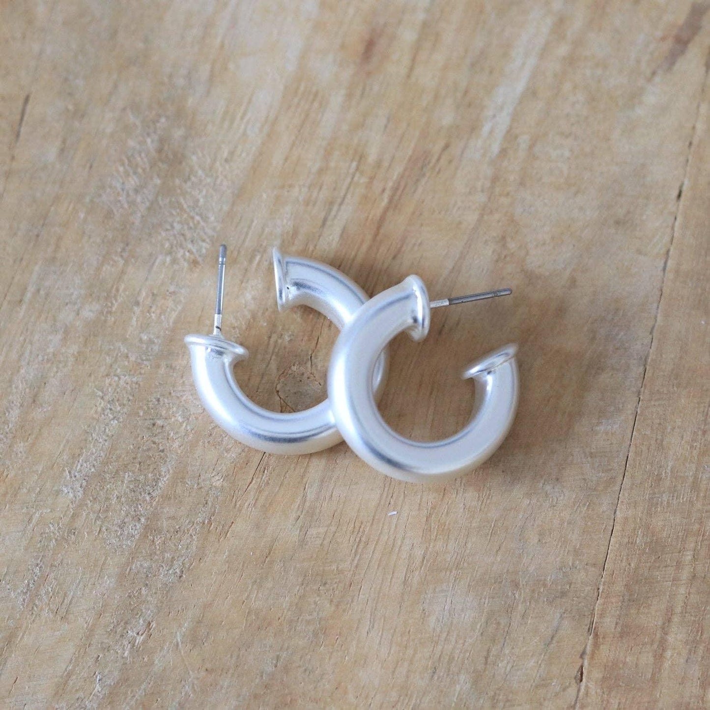Silver chunky hoop earrings on a wooden surface