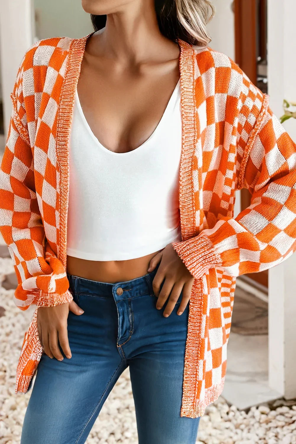 Orange and white checkered knit cardigan with frayed edges, styled with white crop top and blue jeans