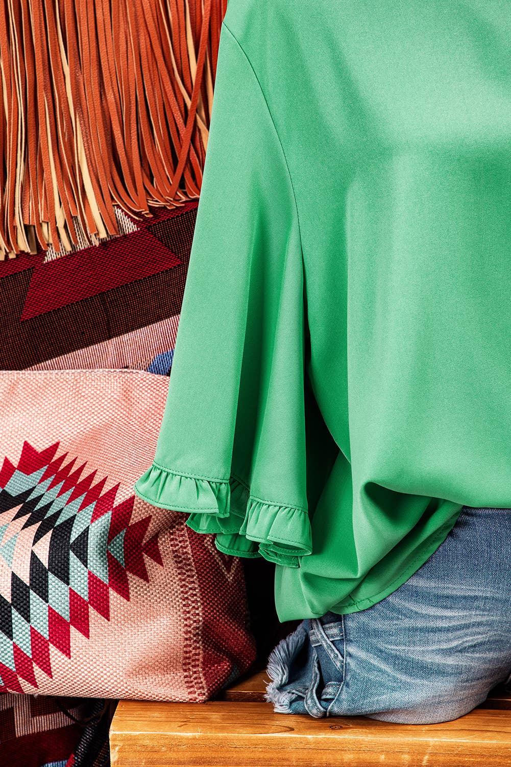 Green ruffled sleeve blouse with fringed bag and denim shorts