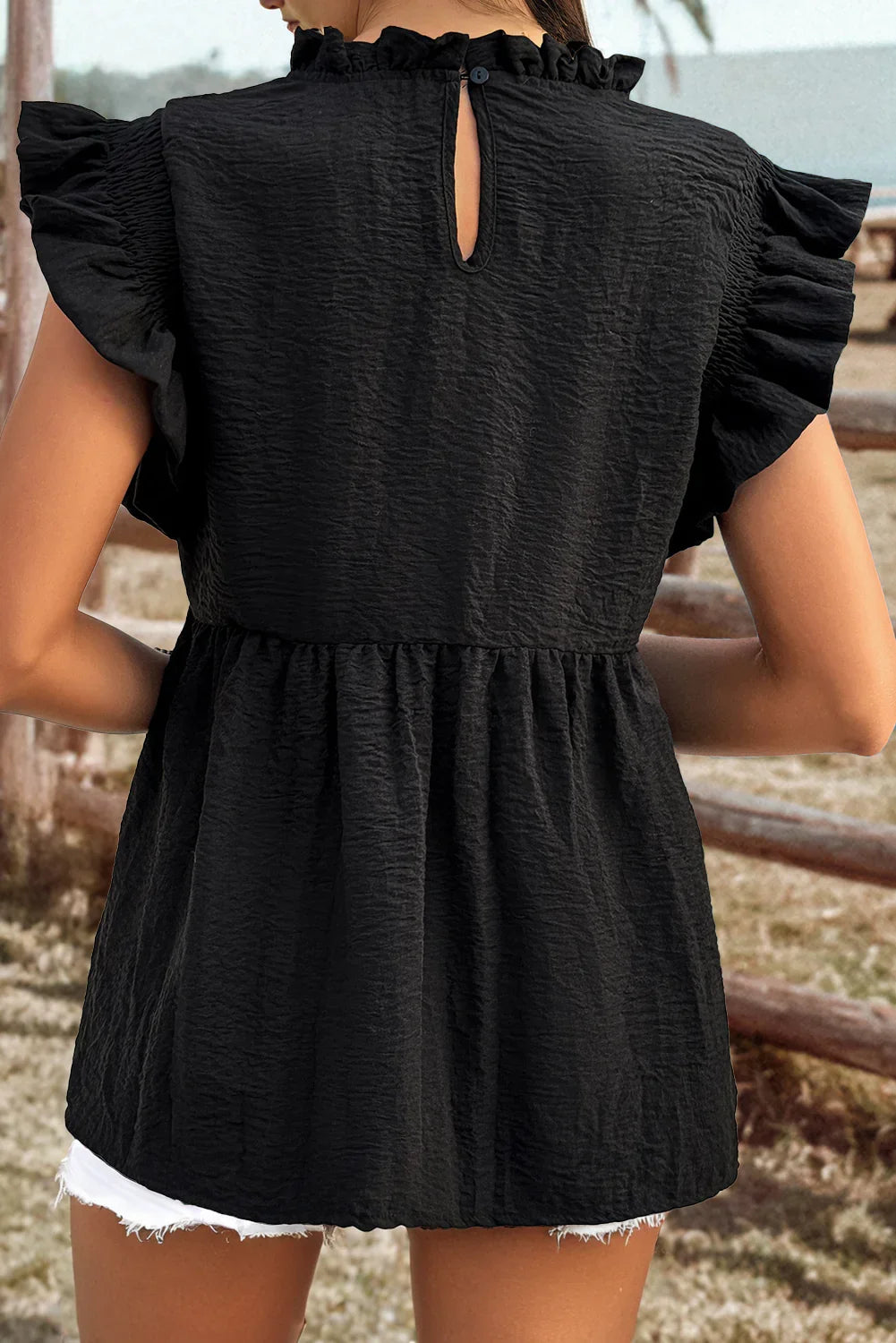 Black ruffled sleeve top with keyhole back, paired with white denim shorts for casual chic style