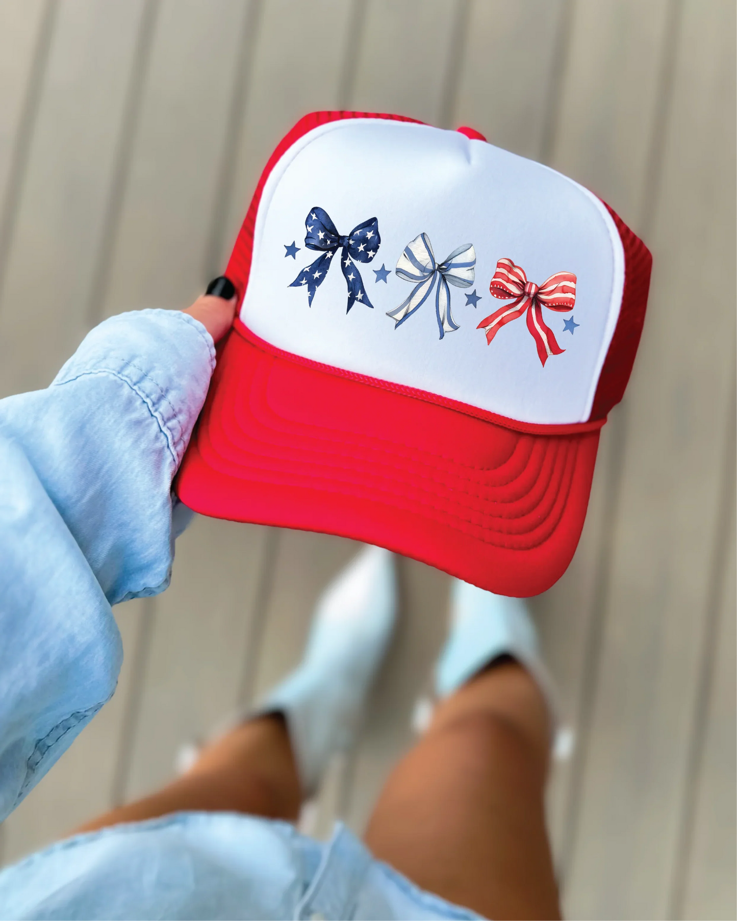 Red and white trucker hat with patriotic bows and stars, perfect for festive occasions.