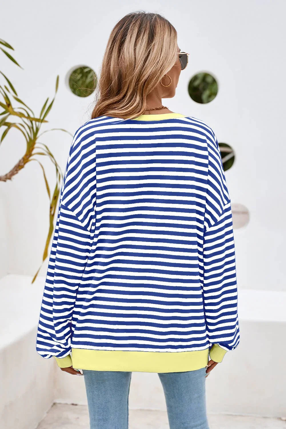 Blue and white striped long-sleeve top with yellow trim, paired with jeans for casual style