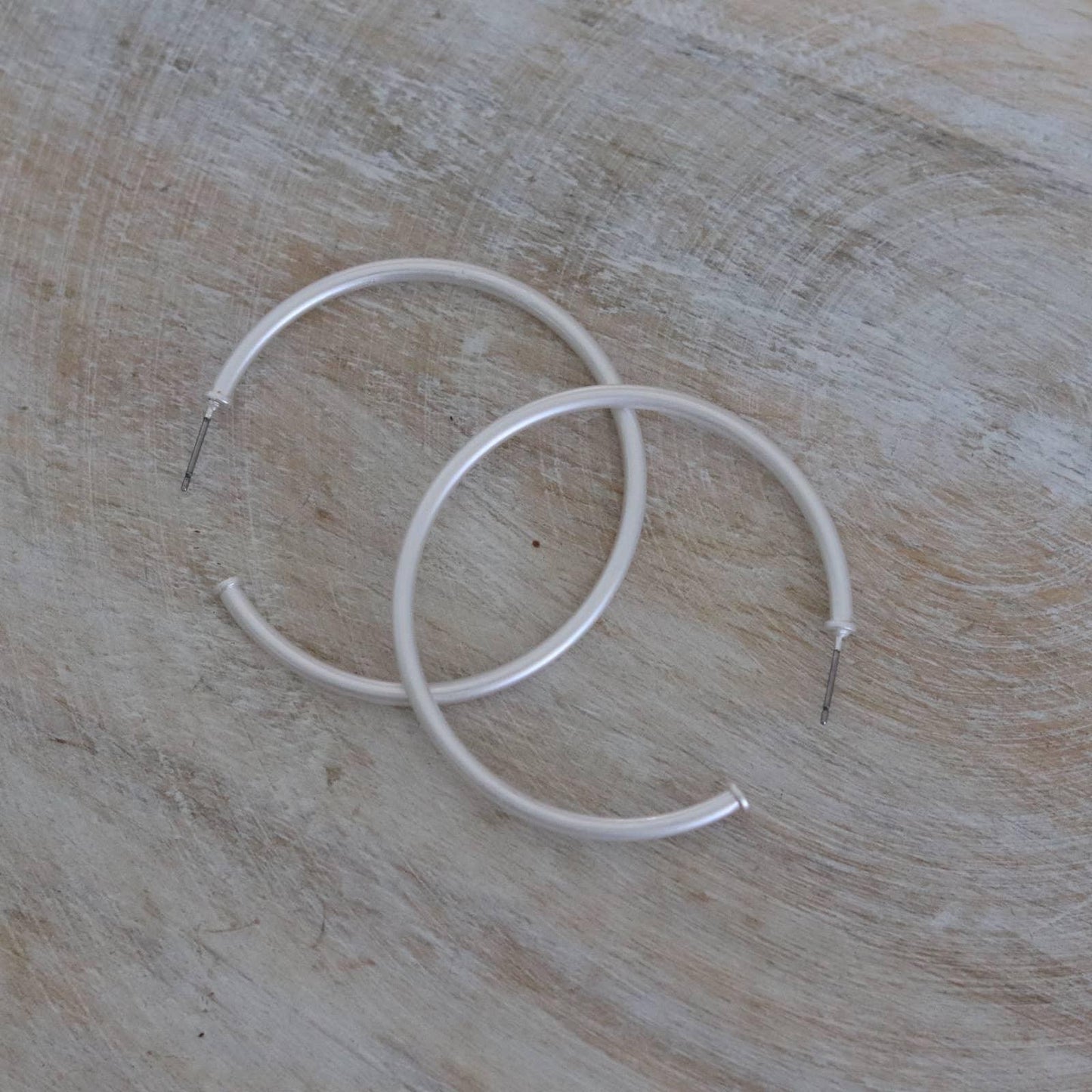 Pair of silver hoop earrings on rustic light wood background