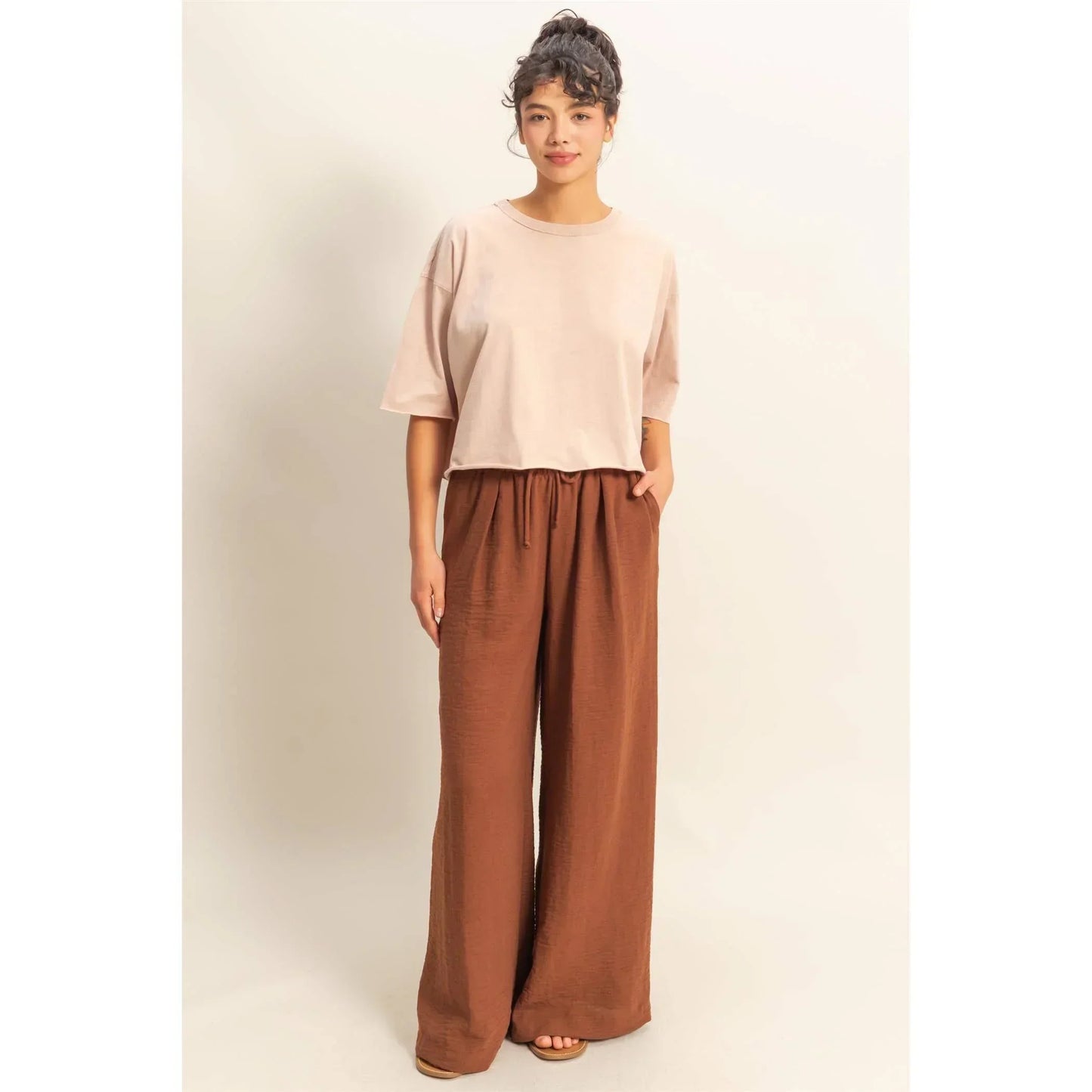 Woman in blush crop top and rust wide-leg drawstring pants, casual chic outfit