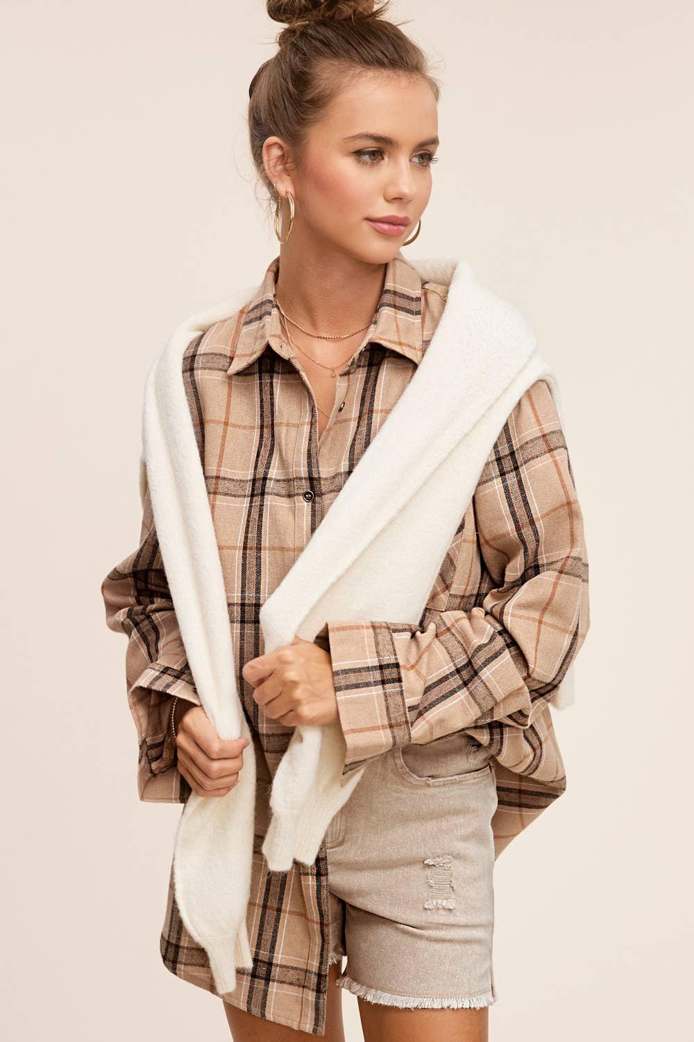Woman wearing plaid flannel shirt, distressed shorts, and layered necklaces