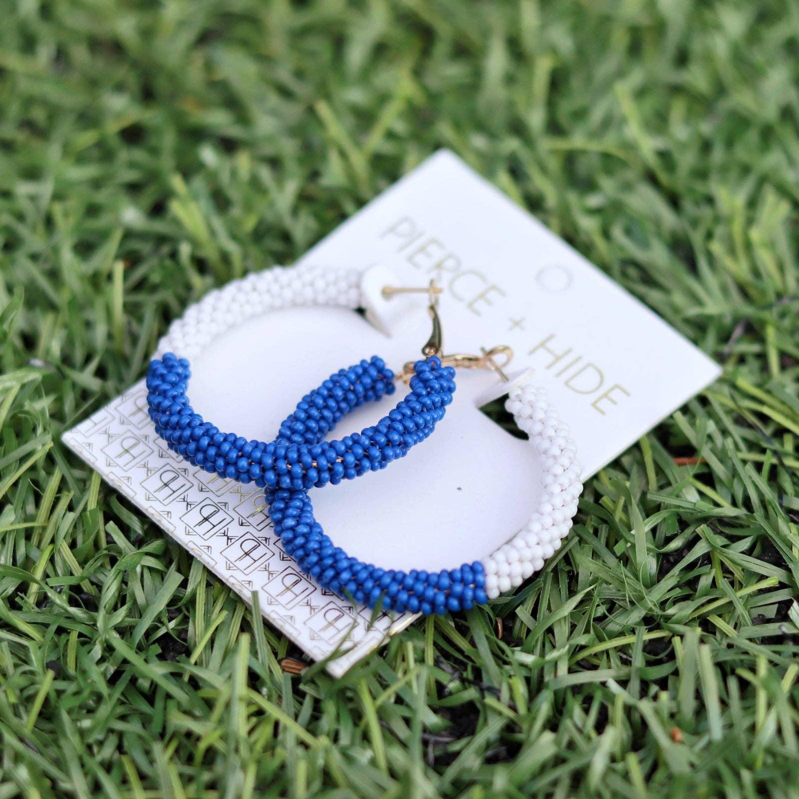 Beaded hoop earrings in blue and white with gold hooks on grass background