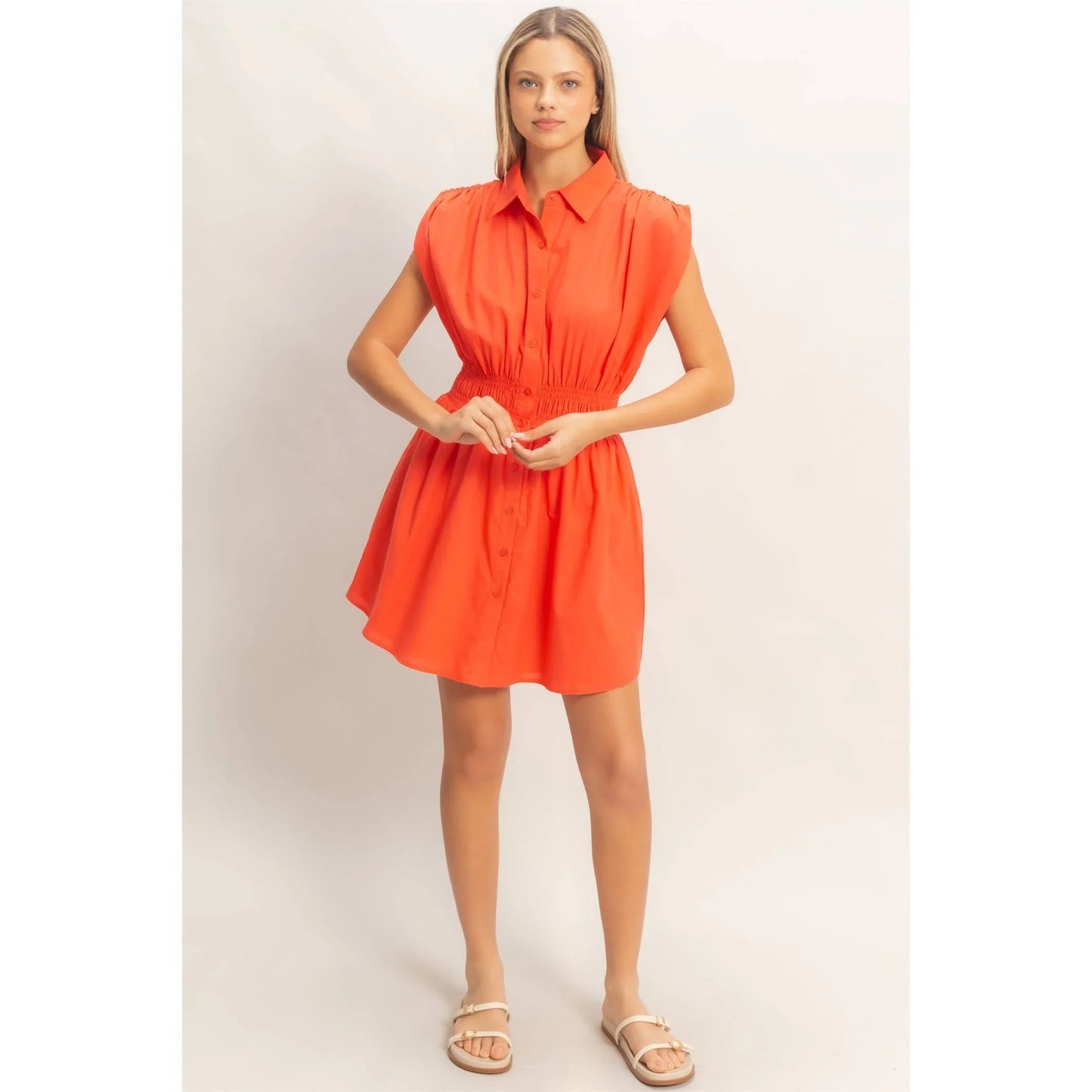 Woman in vibrant orange button-down shirt dress with puff sleeves and cinched waist, paired with sandals