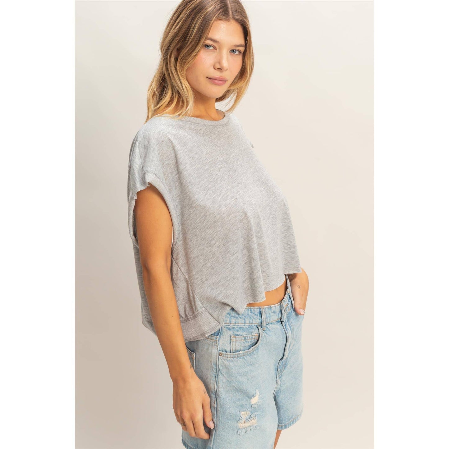 Woman wearing casual grey cropped t-shirt and light wash denim shorts