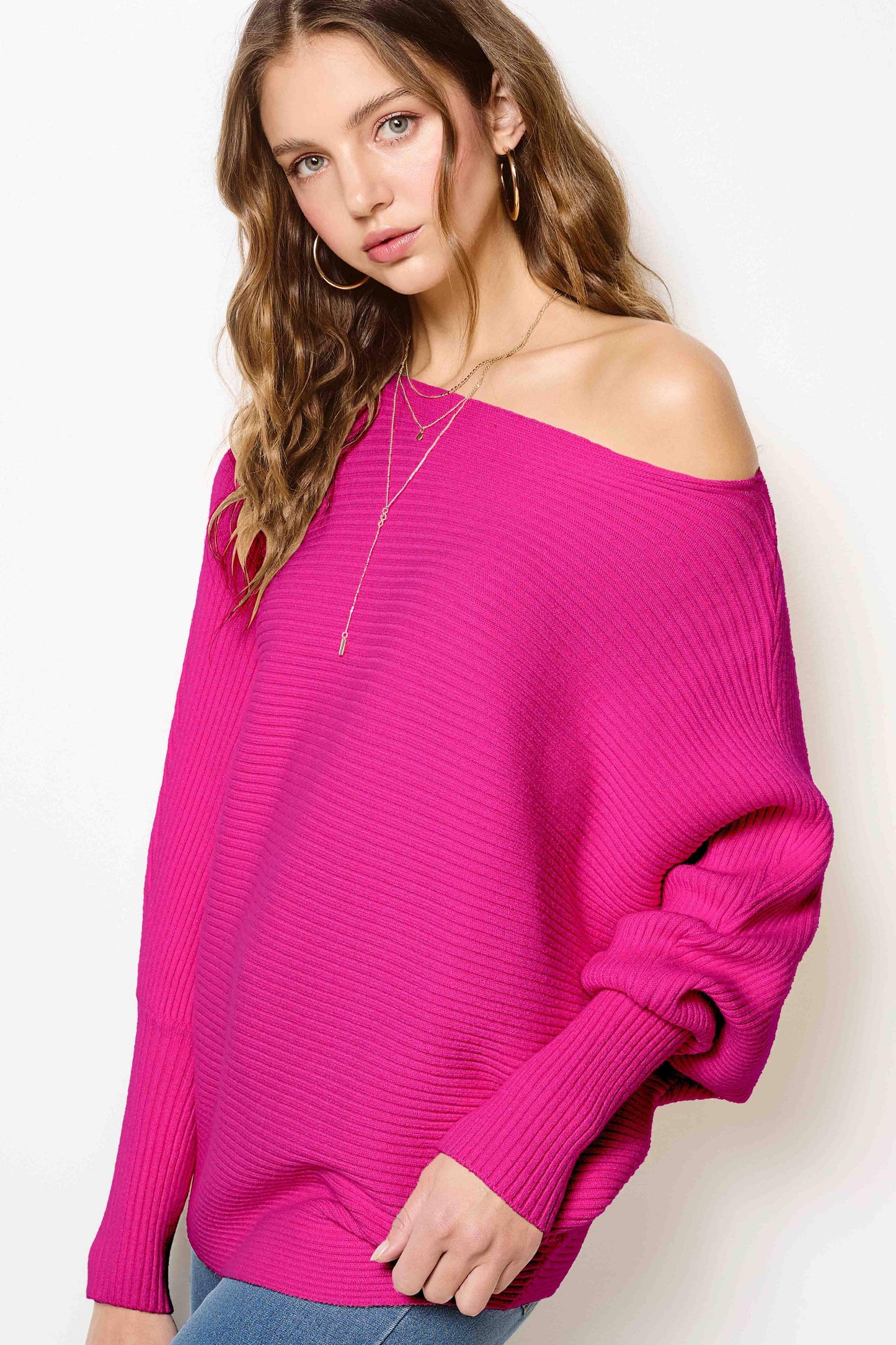 Woman wearing a hot pink off shoulder ribbed sweater and jeans