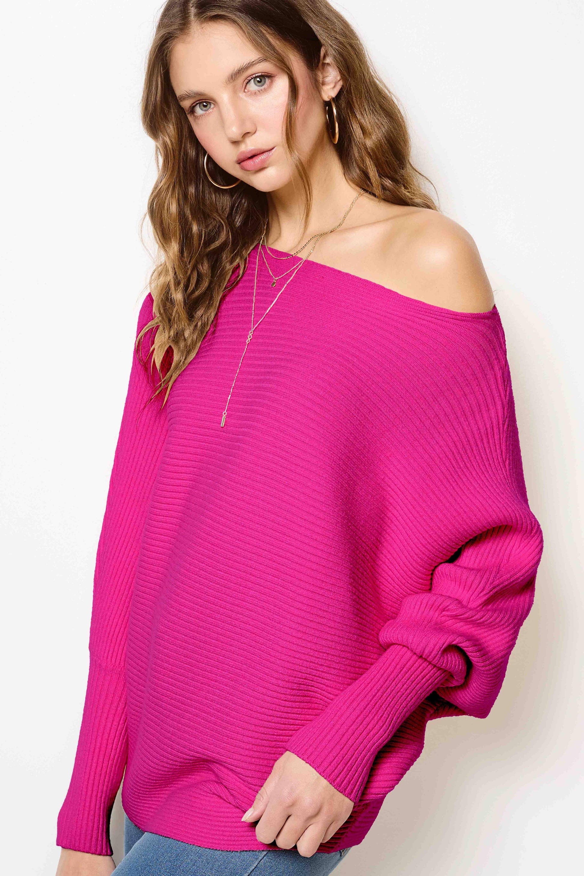 Woman wearing a hot pink off shoulder ribbed sweater and jeans