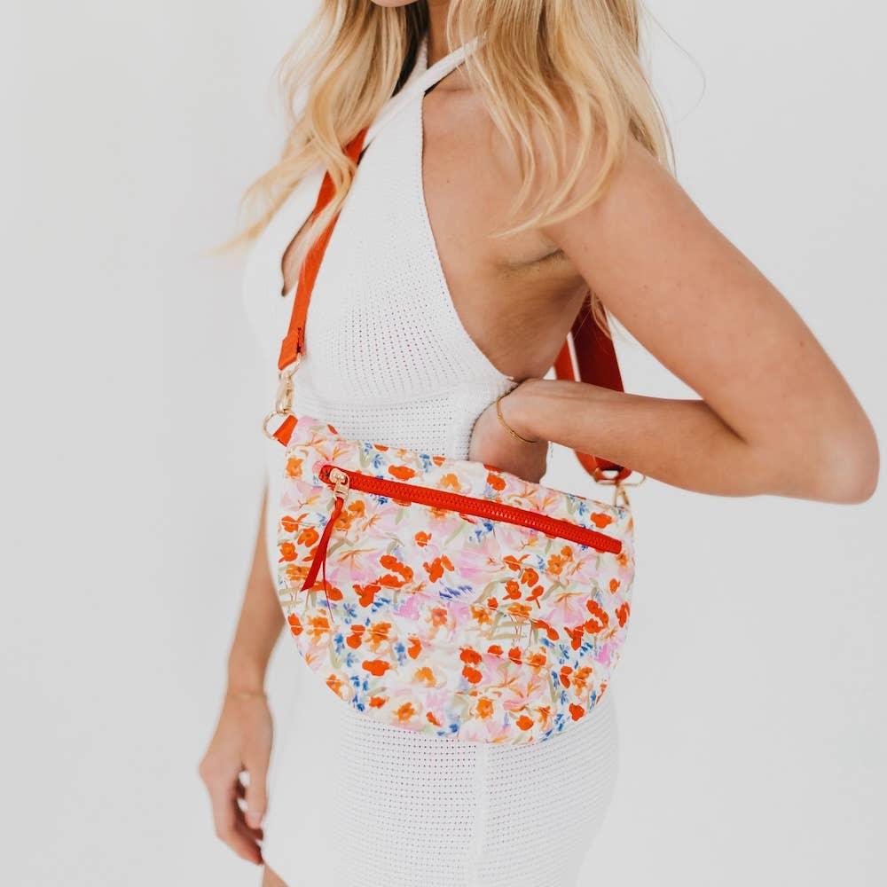 Floral crossbody bag with orange strap, worn with white knit dress for stylish summer look