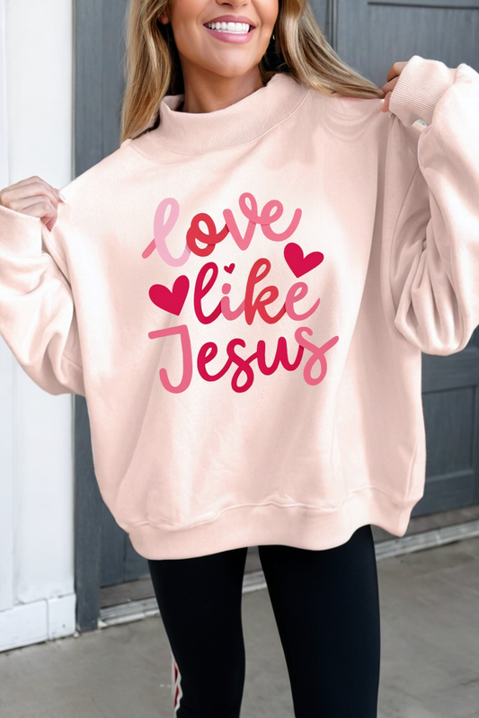 Woman wearing light pink sweatshirt with 'love like Jesus' and heart graphics, casual fashion
