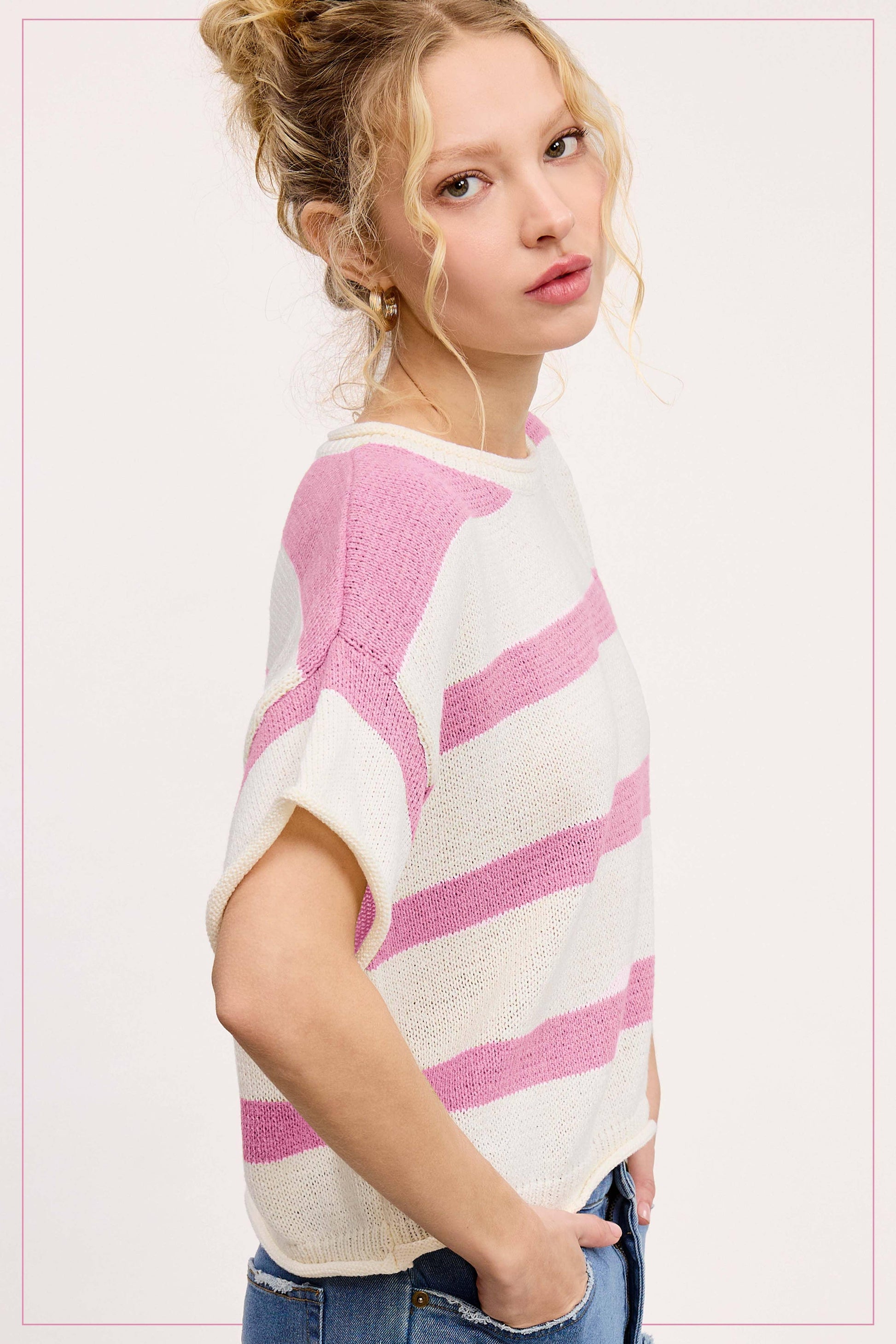 Woman wearing a short sleeve white and pink striped knit sweater with blue jeans