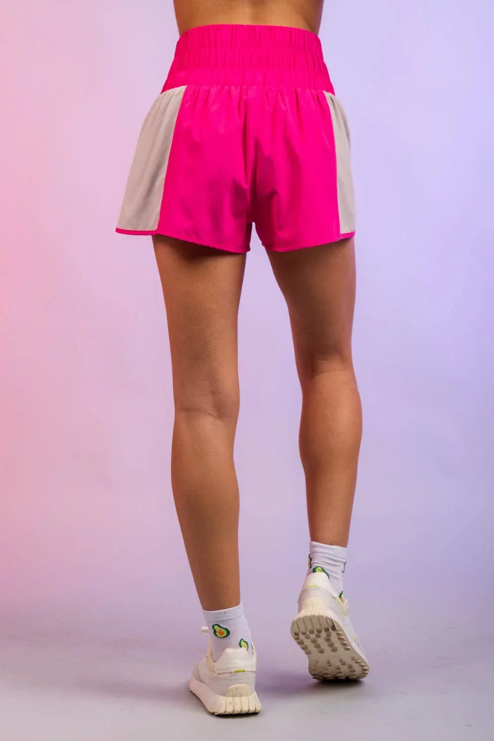 Back view of person wearing hot pink athletic shorts with white side panels and sneakers