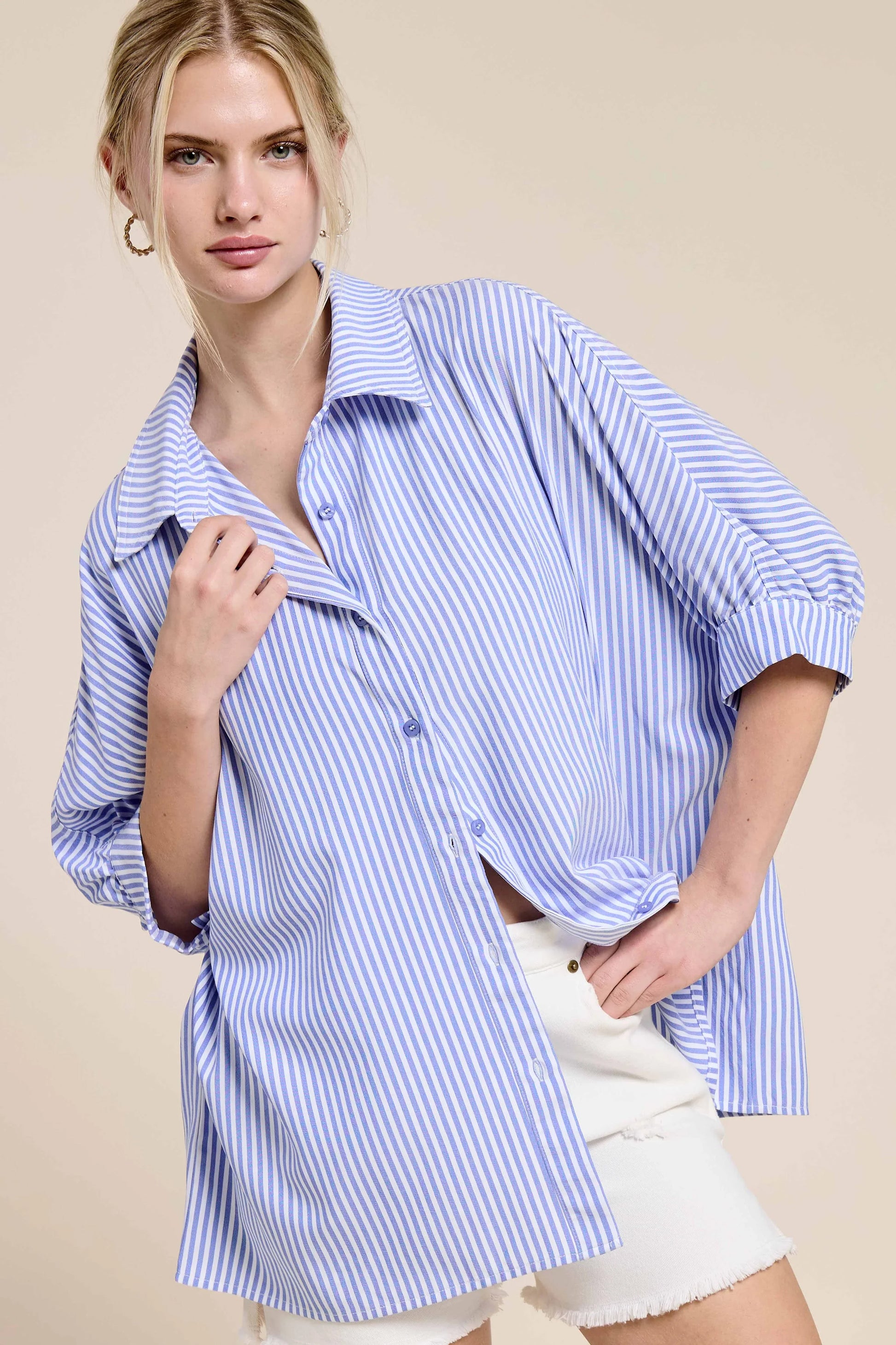 Woman wearing an oversized blue and white striped button-up shirt with white shorts