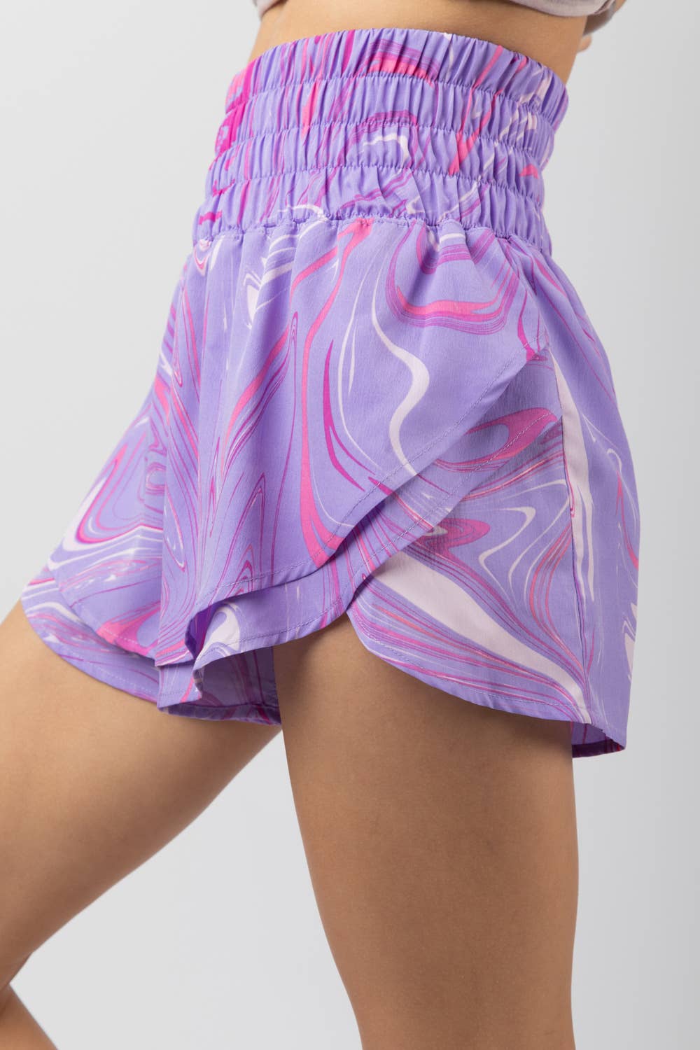 Woman wearing high-waisted purple and pink swirl print shorts with elastic waistband