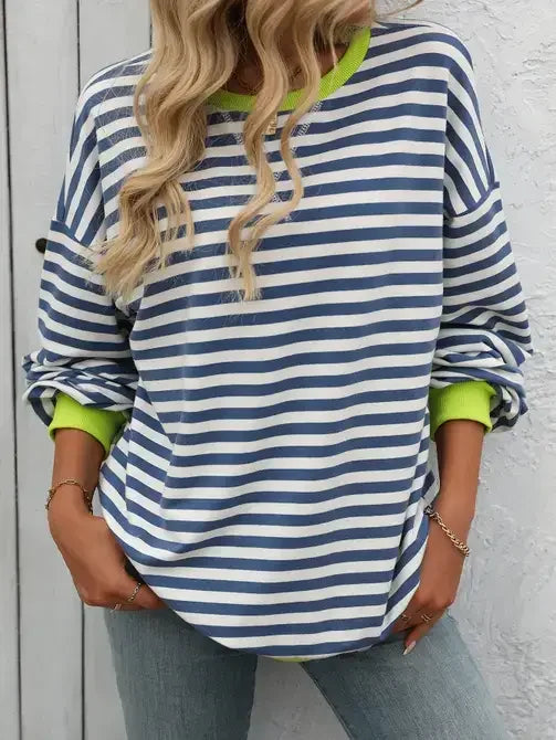 Woman wearing blue and white striped long sleeve shirt with neon green accents and jeans
