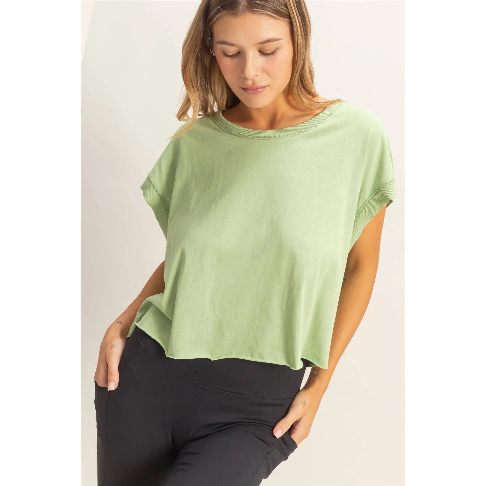 Woman wearing loose green short sleeve top and black leggings, casual fashion
