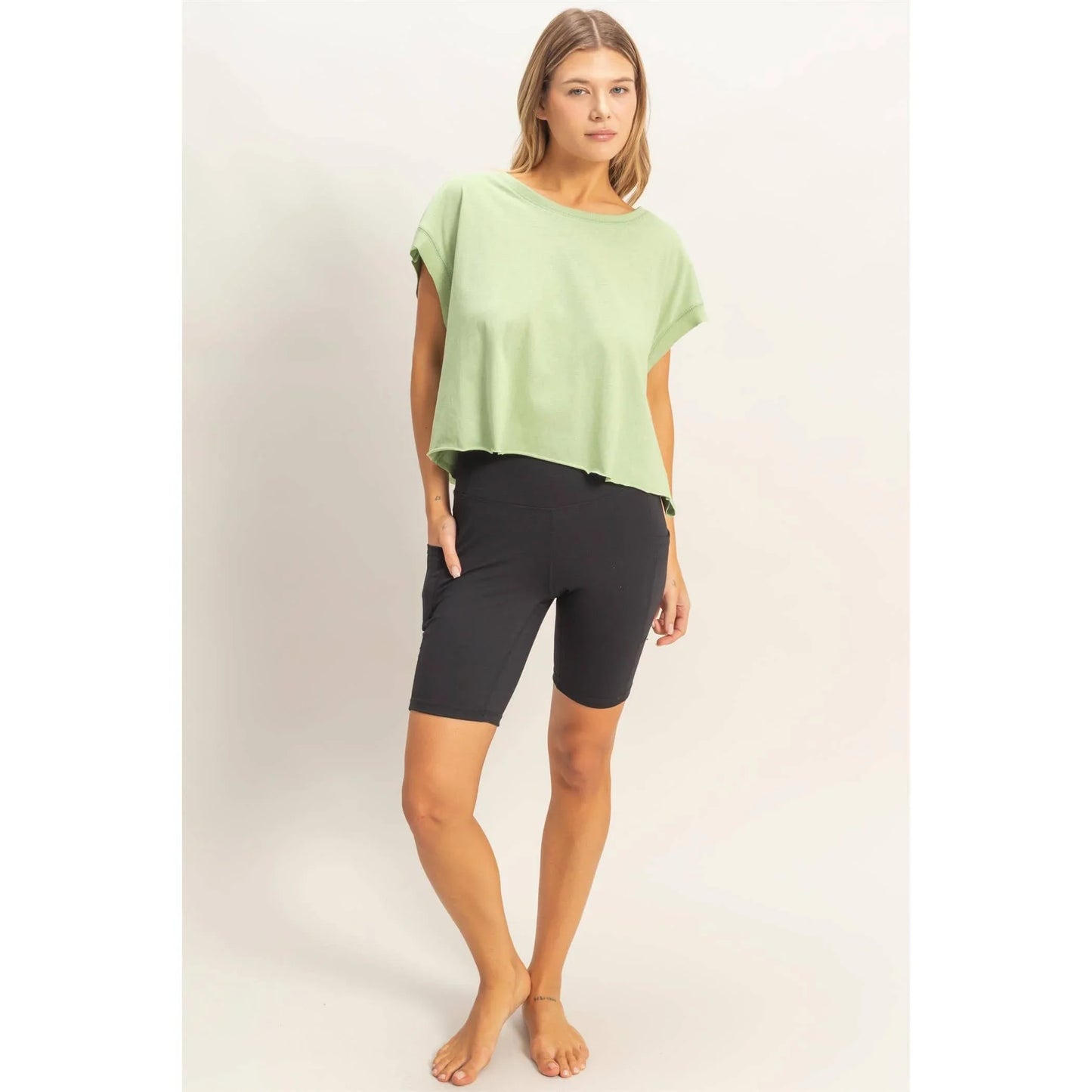 Woman wearing mint green oversized t-shirt and black biker shorts on white background