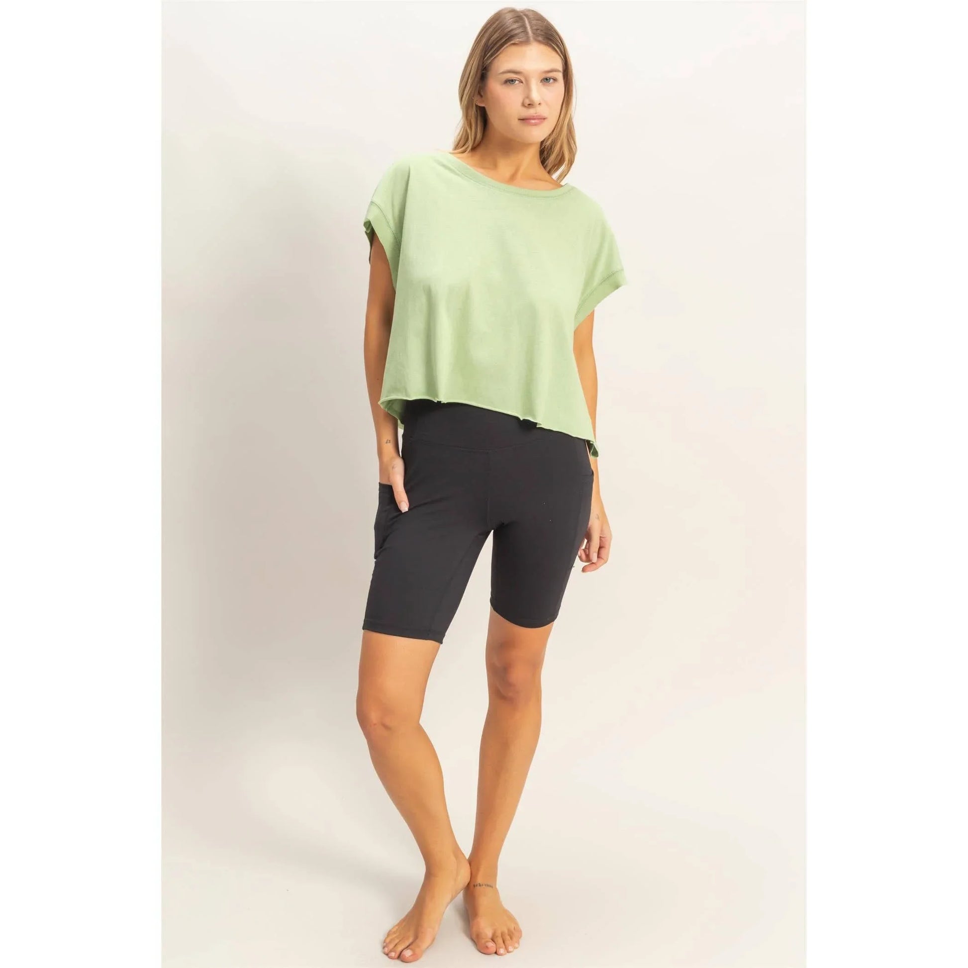 Woman wearing mint green oversized t-shirt and black biker shorts on white background
