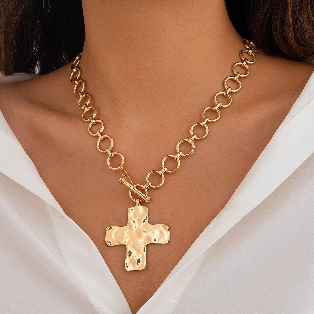 Gold chunky chain necklace with hammered cross pendant worn over a white blouse