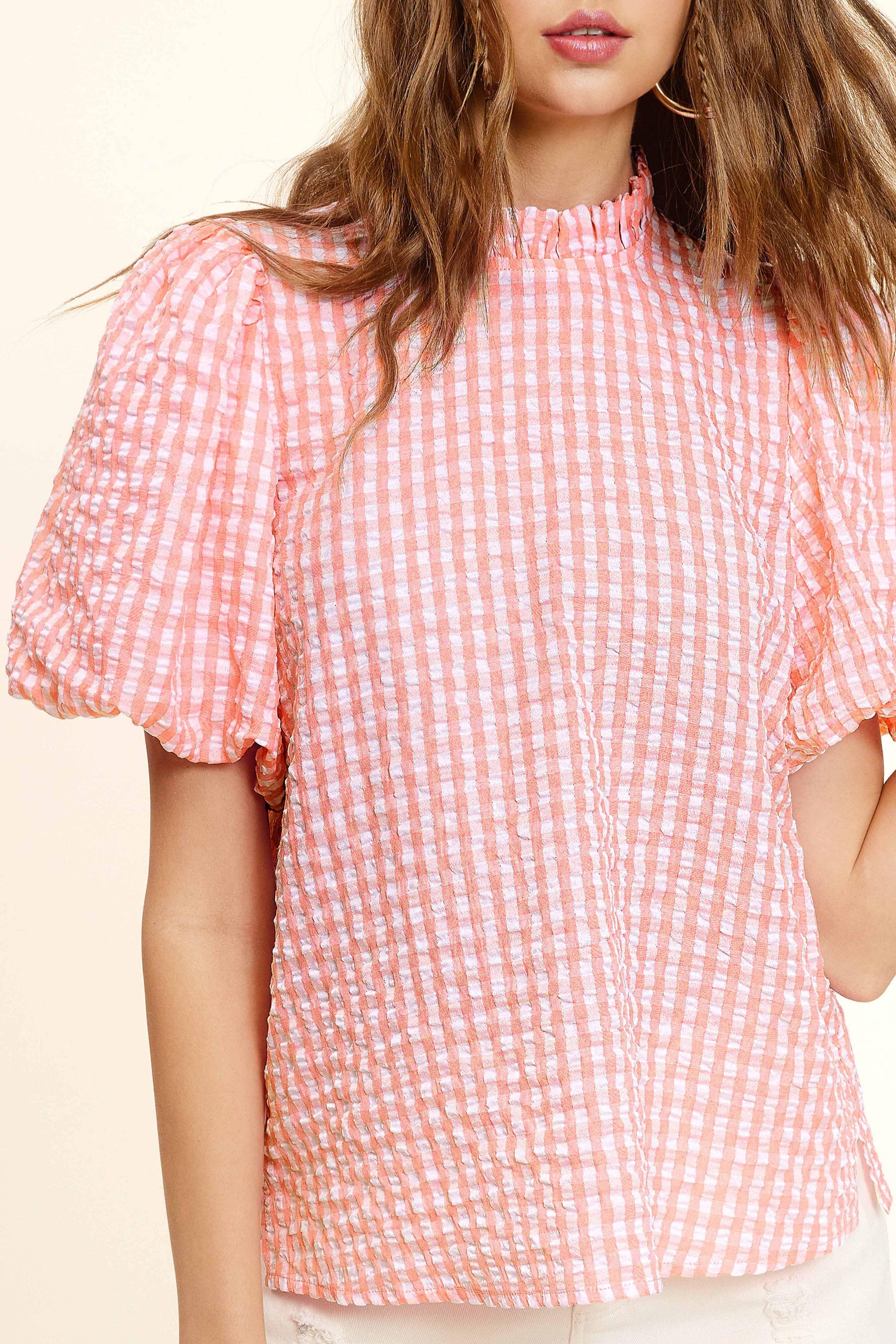 Woman wearing pink and white gingham puff sleeve blouse from Lou's Boutique