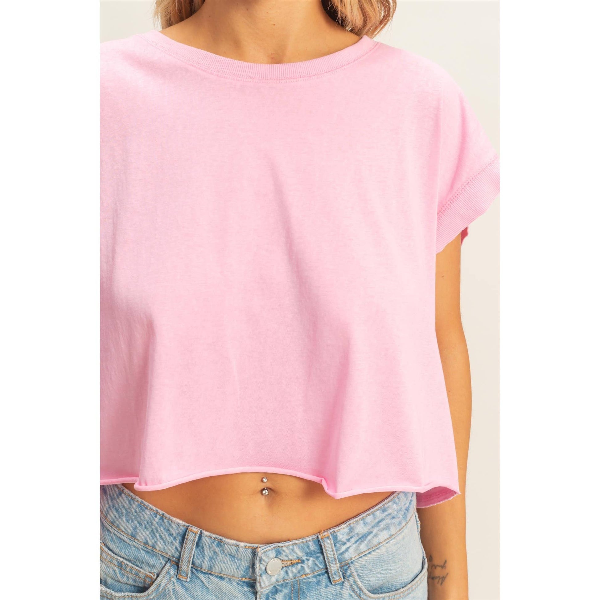Light pink cropped t-shirt with rolled sleeves, paired with high-waisted blue denim jeans