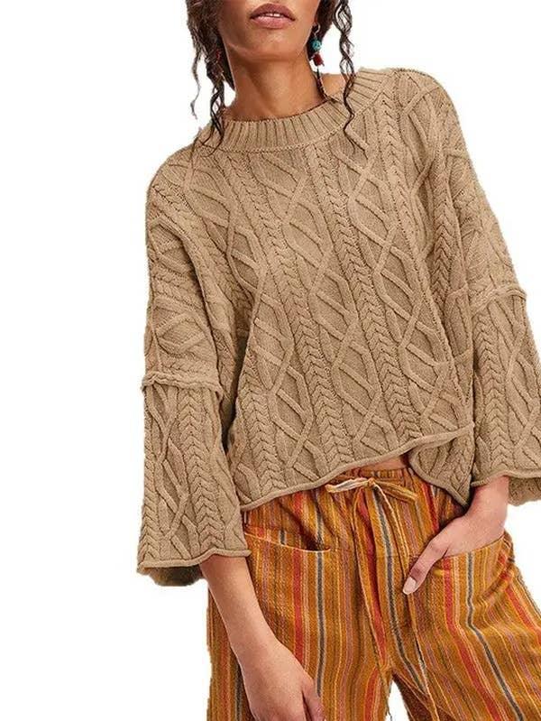 Woman wearing a tan cable knit sweater and striped loose-fit pants