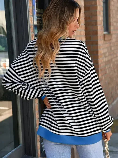 Woman wearing black and white striped long sleeve shirt with blue trim, casual style