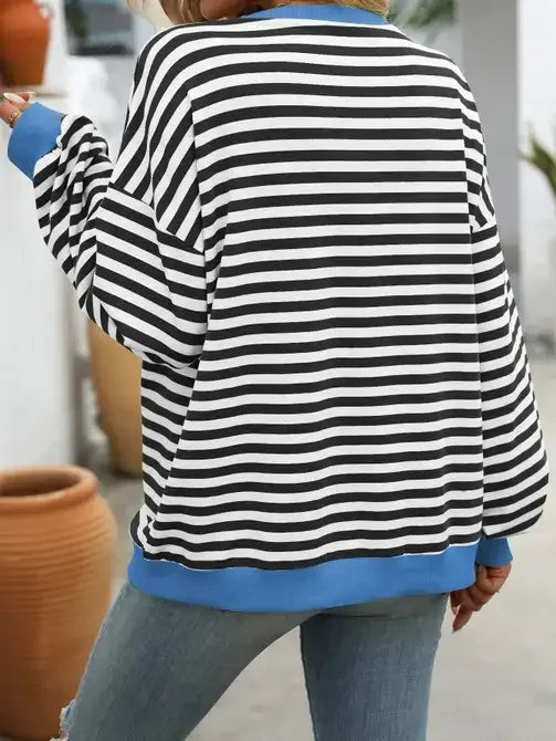 Woman wearing black and white striped sweater with blue cuffs and hem, casual outfit