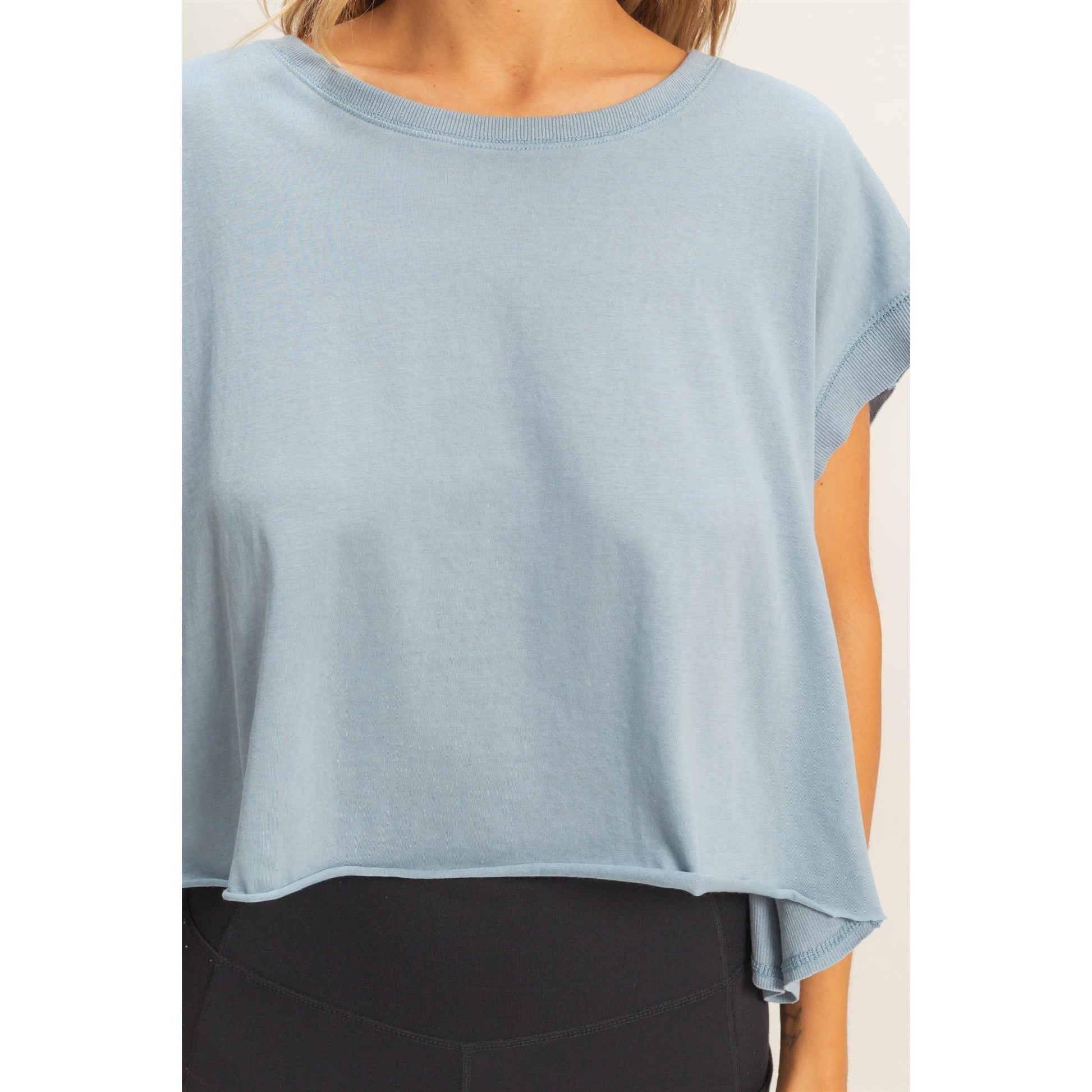 Woman wearing a loose light blue short sleeve top with black leggings