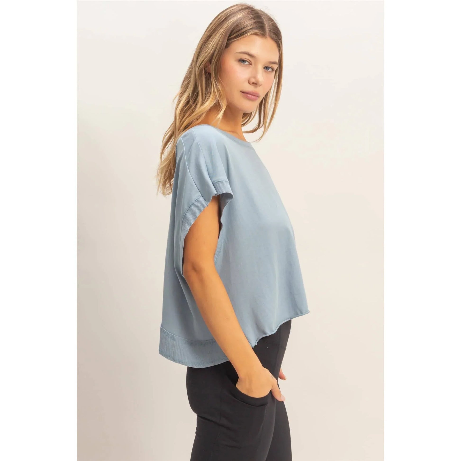 Woman wearing light blue loose short-sleeve top and black pants, casual fashion
