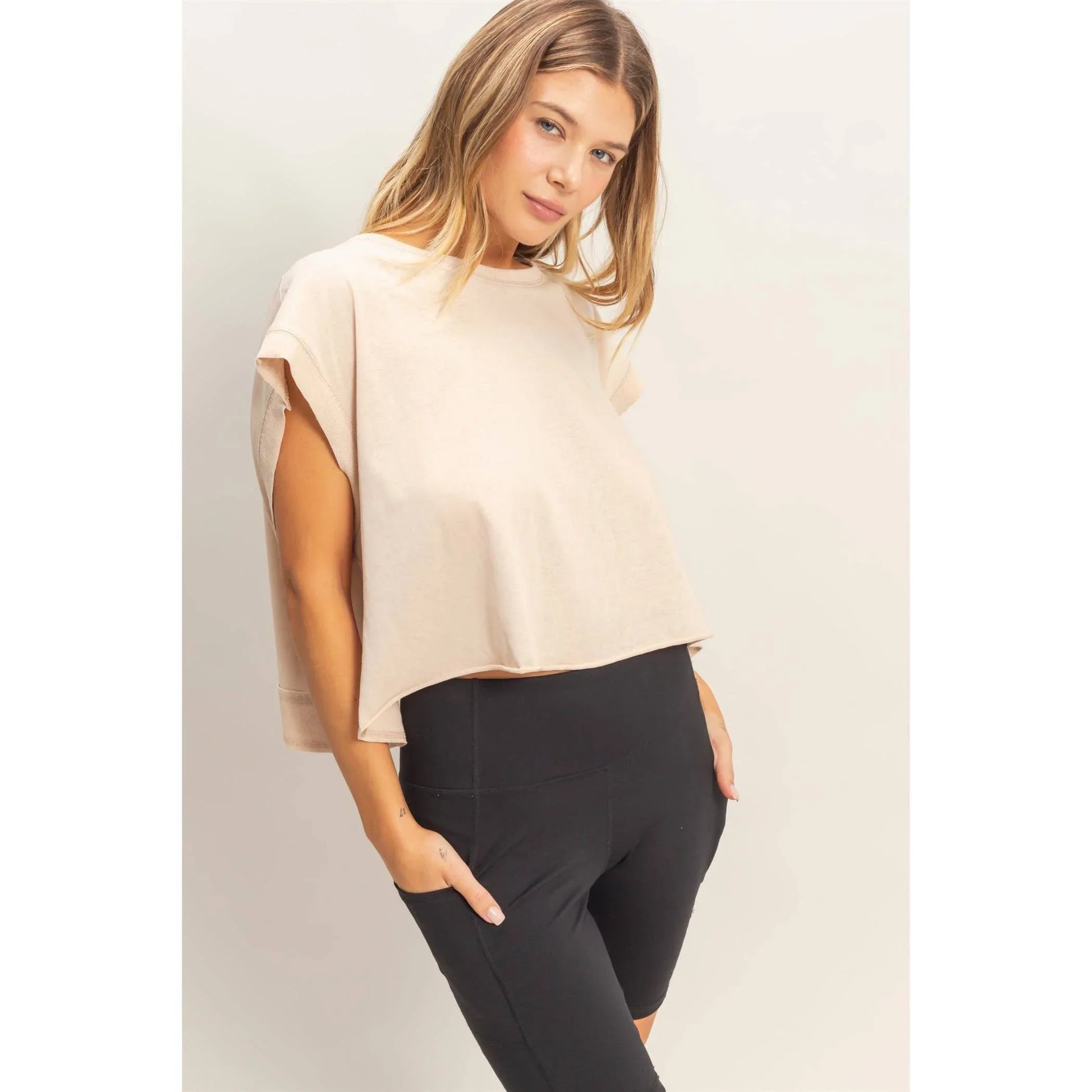 Woman wearing a beige short sleeve boxy top and black high-waisted leggings