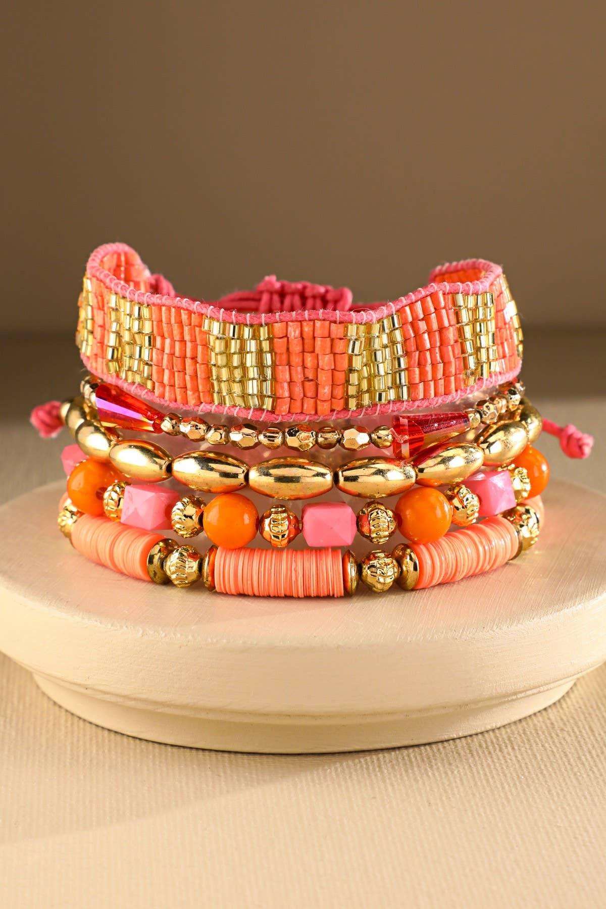 Stack of colorful beaded bracelets with gold, coral, and orange accents on display stand