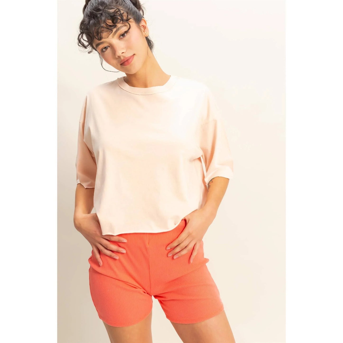 Woman in blush oversized tee and coral ribbed shorts, stylish casual outfit