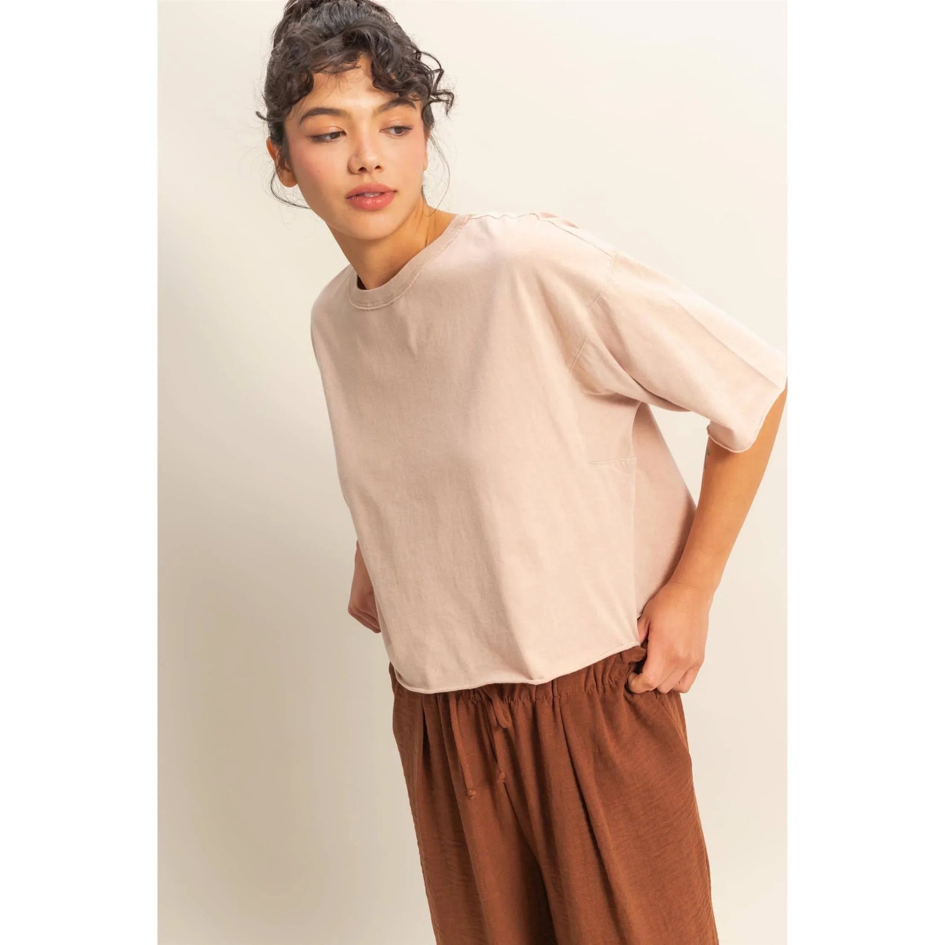 Woman modeling blush oversized t-shirt with relaxed fit and brown wide-leg pants, casual fashion outfit