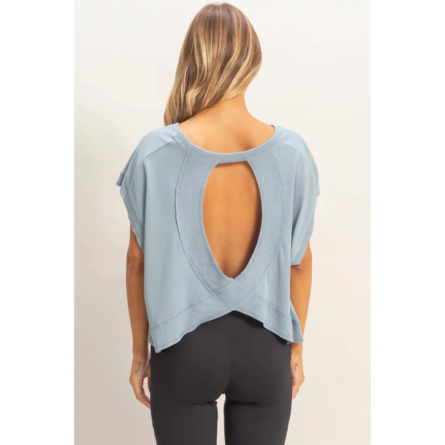 Woman wearing a light blue open back top with short sleeves and black leggings