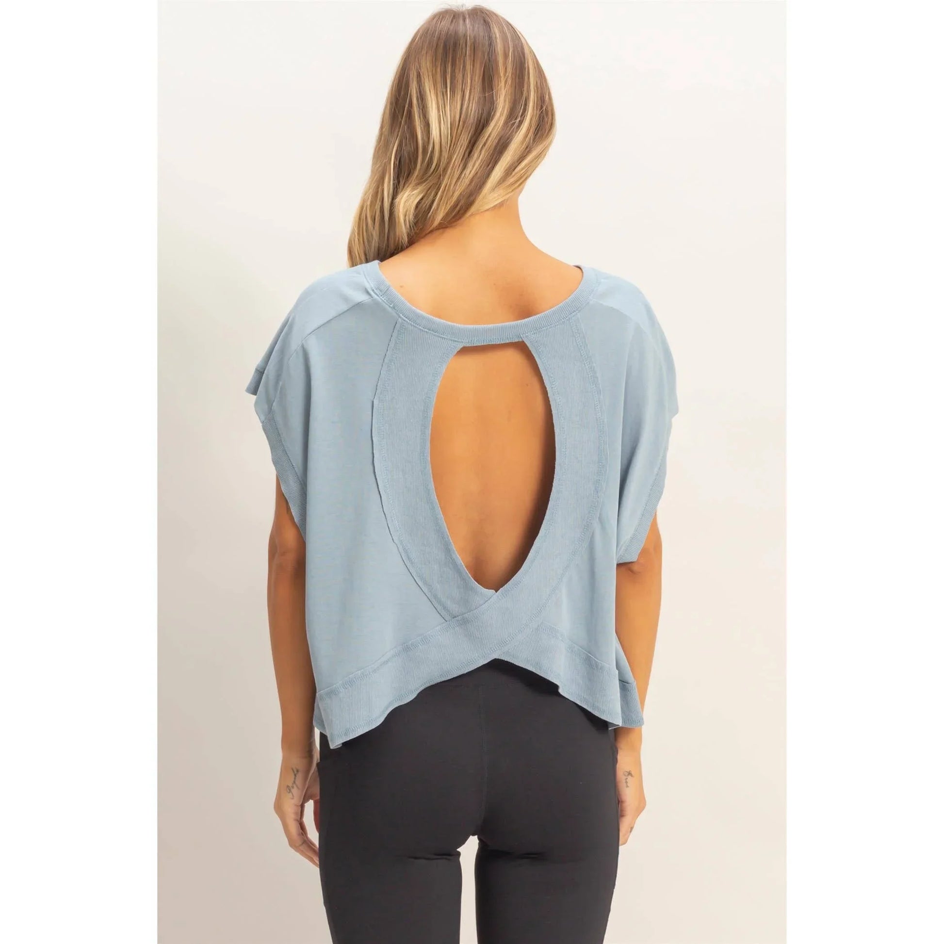 Woman wearing a light blue open back top with short sleeves and black leggings