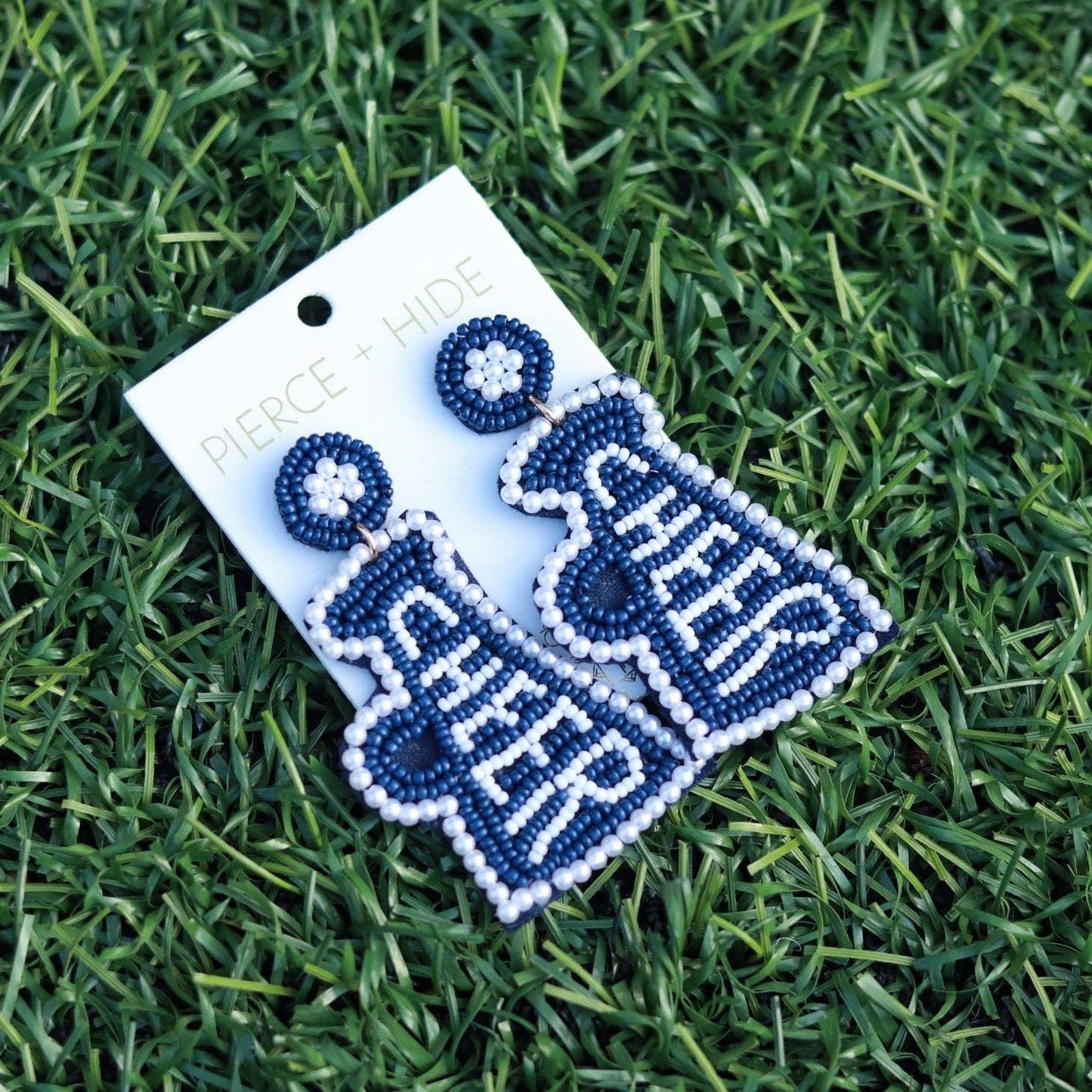 Blue and white beaded cheer megaphone earrings on grass background
