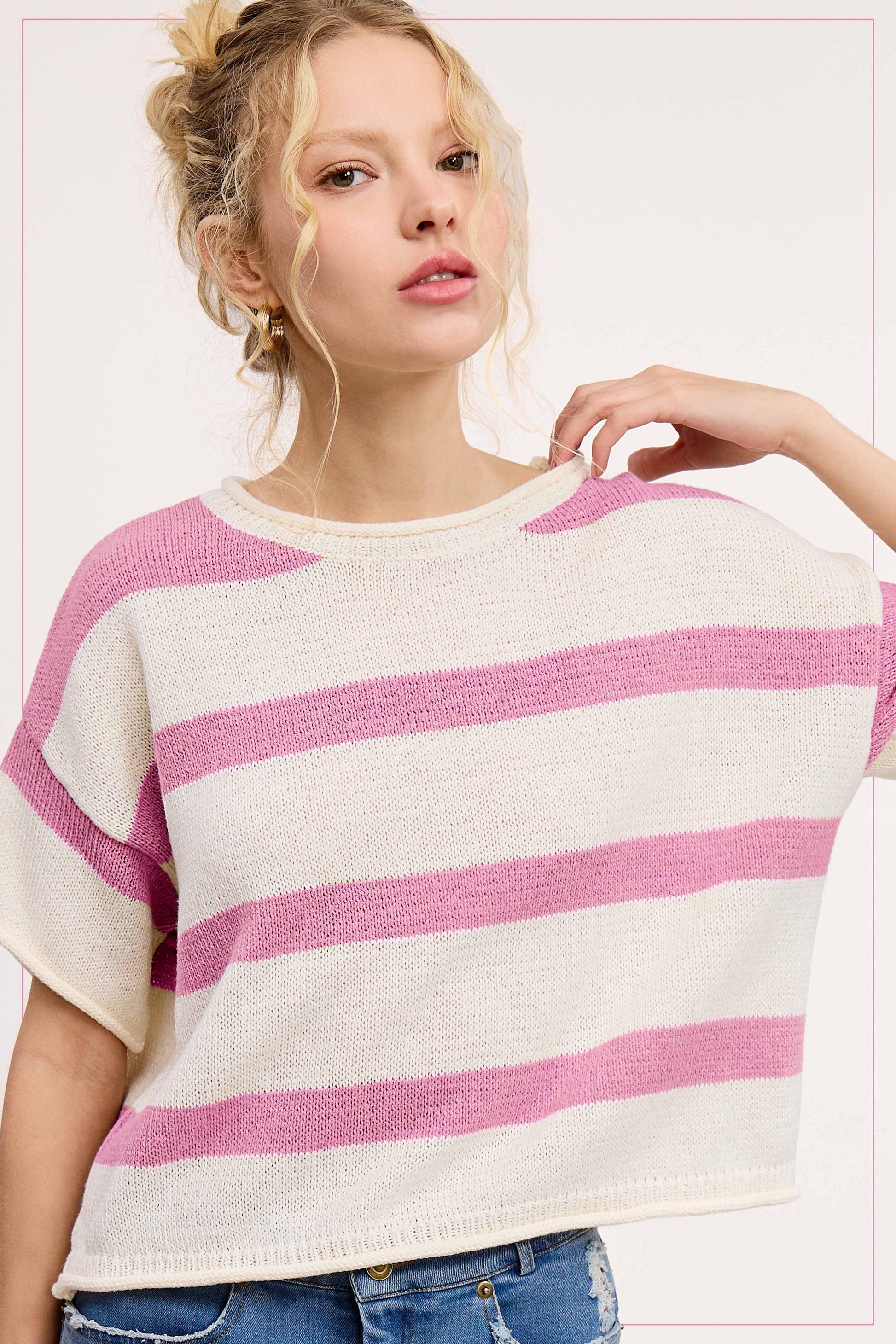 Woman wearing a casual short-sleeve cream and pink striped knit sweater with jeans