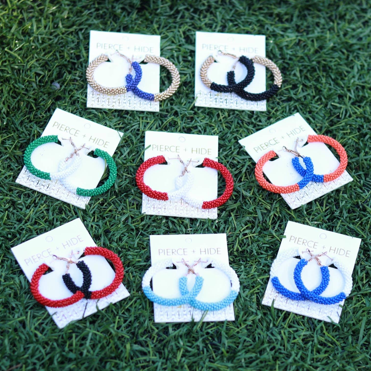 Colorful beaded hoop earrings on display cards, arranged on grass background