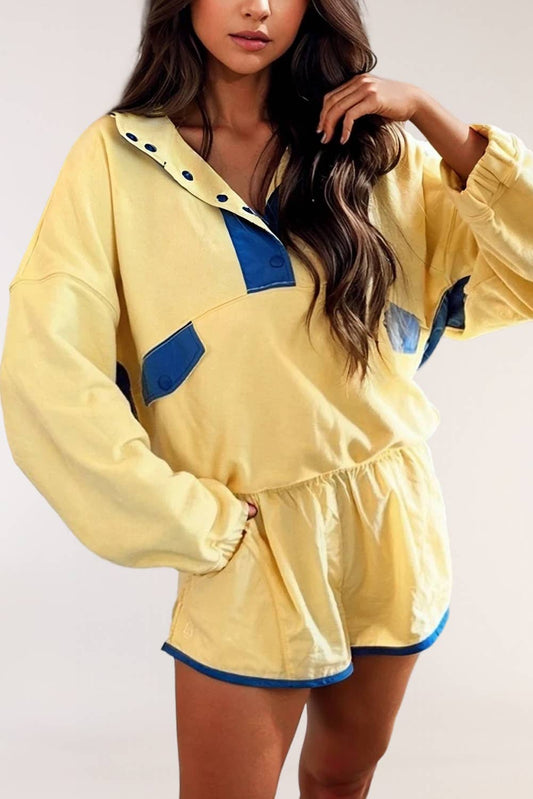 Woman wearing yellow and blue colorblock long sleeve romper with snap buttons