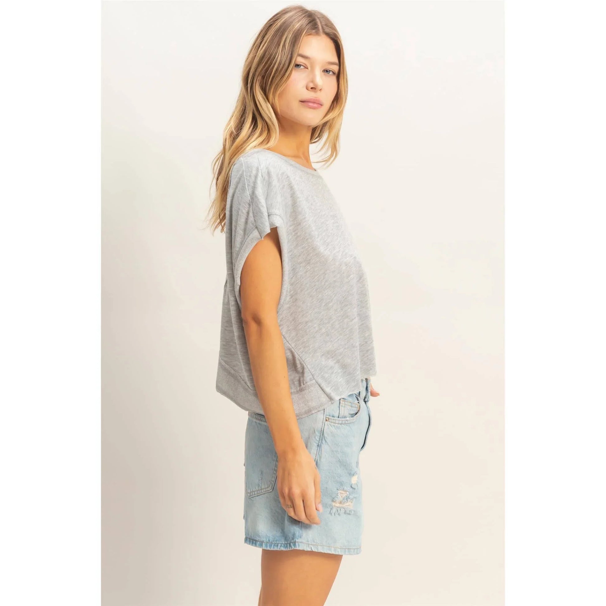 Woman wearing a loose grey t-shirt and light blue denim skirt, casual fashion look
